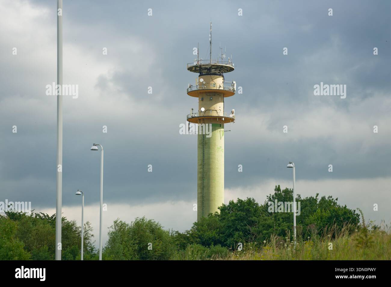 Un'alta colonna come una torre si erge con tre livelli di antenna distanziati verso l'alto. Ogni livello è dotato di pannelli montati intorno all'anello, creando un silho per telecomunicazioni a strati Foto Stock