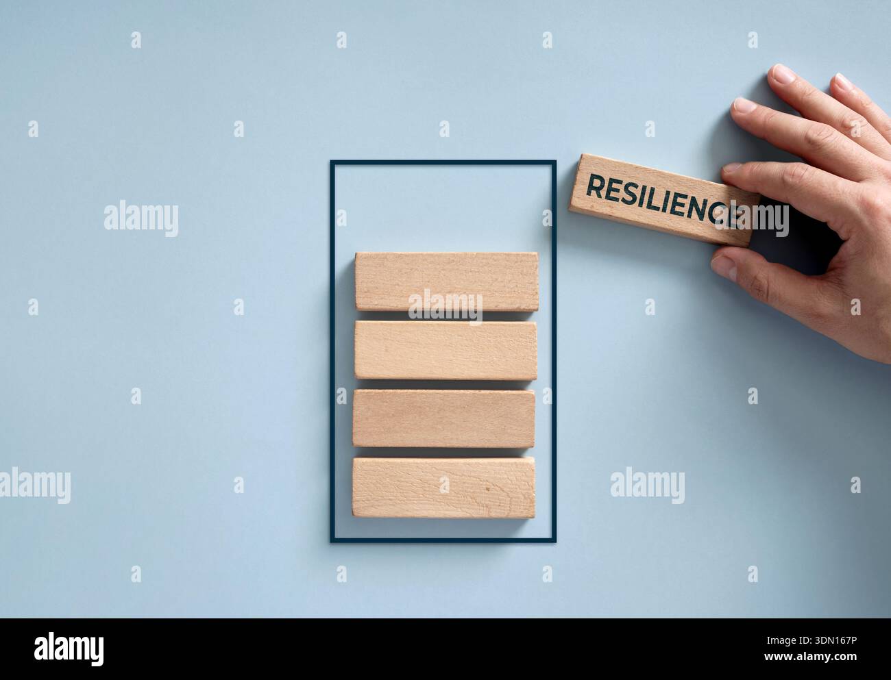 Posizionare a mano un blocco di legno con la parola "resilienza" sopra gli altri blocchi, a simboleggiare una batteria piena di energia e potenza Foto Stock