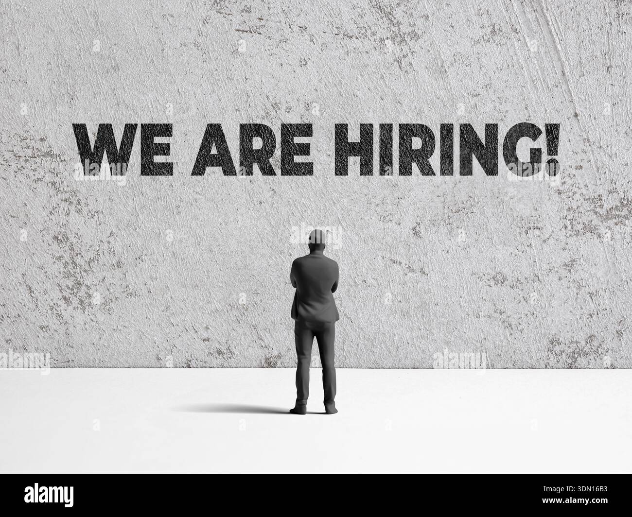 Persona d'affari in piedi, guardando We Are Hiring dipinto su un muro di cemento, che rappresenta la ricerca di un lavoro e il reclutamento Foto Stock