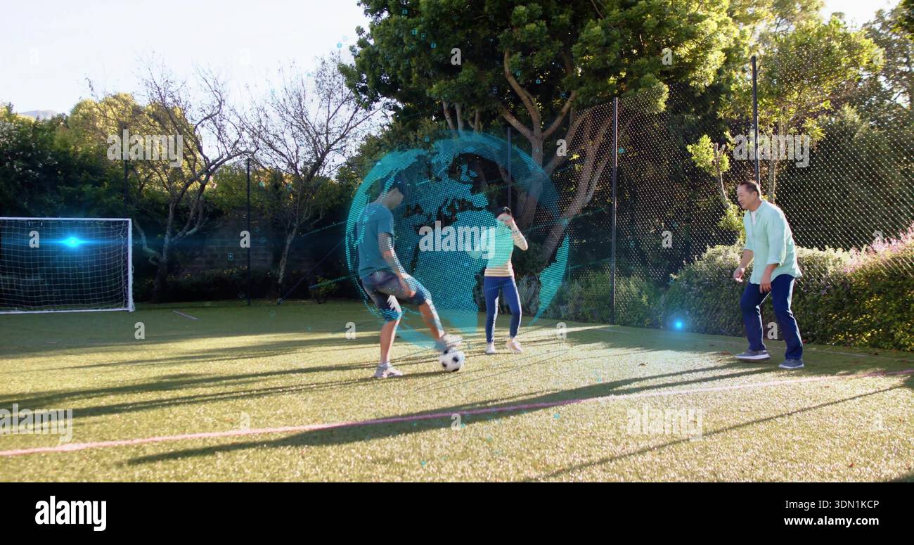 Giocare a tre adulti con abiti sportivi, calciare la palla su un piccolo prato, con globo olografico Foto Stock