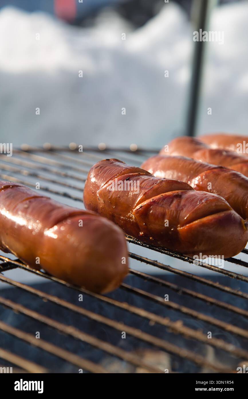 Salsicce grigliate su un barbecue in un ambiente all'aperto innevato. Foto Stock