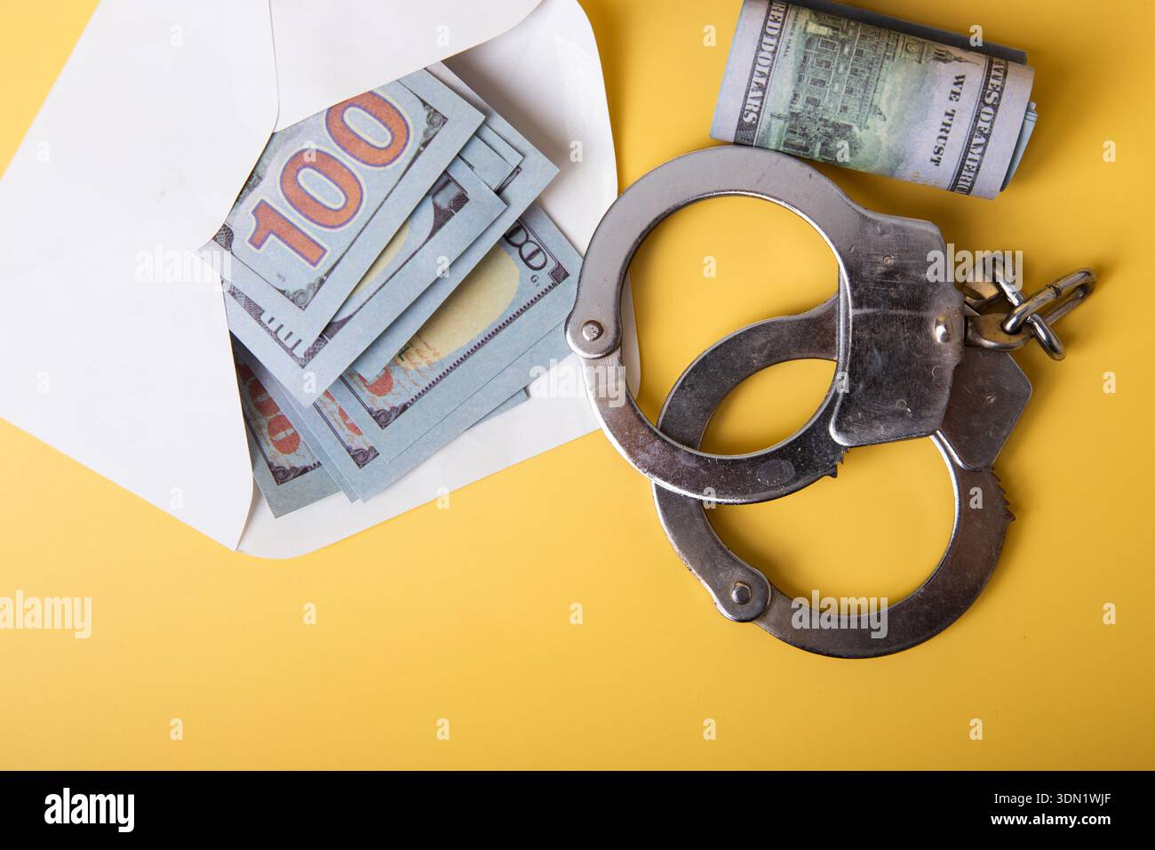 Manette e denaro in una busta che rappresenta attività illegali come tangenti e frodi Foto Stock