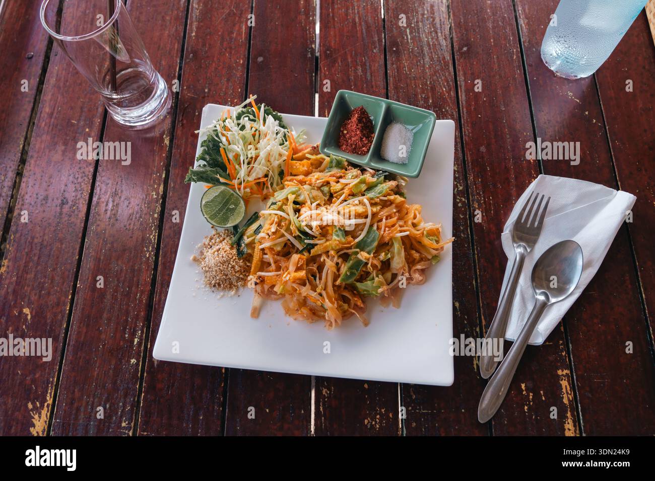 Spaghetti fritti thailandesi su un piatto quadrato bianco su un tavolo di legno in un ristorante rustico all'aperto. Vista dall'alto di Flat Lay Real dish nella vita reale Foto Stock