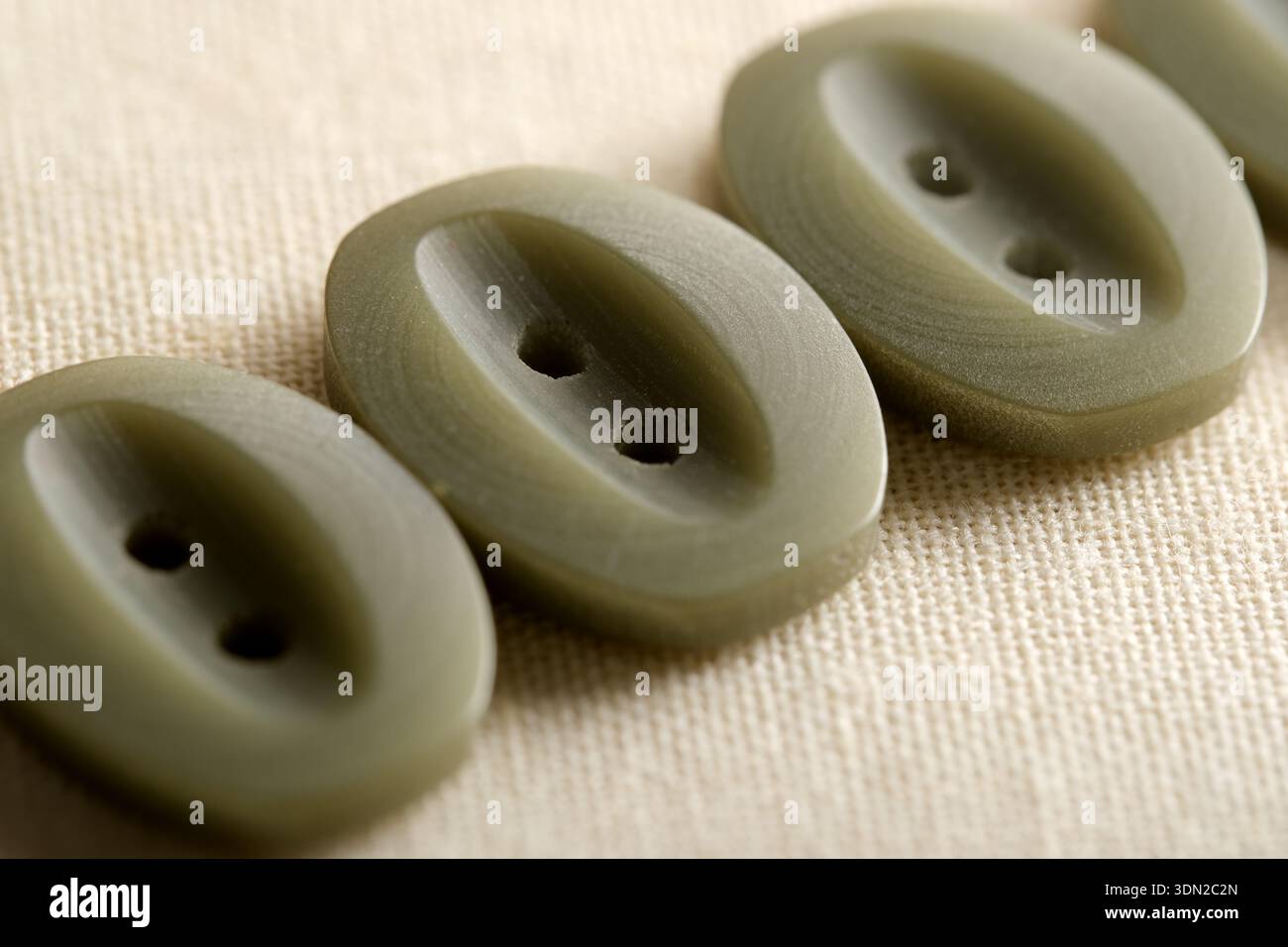 I morbidi pulsanti verdi si allineano perfettamente su uno sfondo crema testurizzato, in attesa di essere utilizzati. Foto Stock