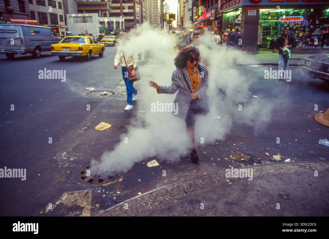 NOI, New York City, Una donna che sta andando al lavoro attraversa una strada mentre il vapore sale da una stazione della metropolitana sotto la città. Foto Stock