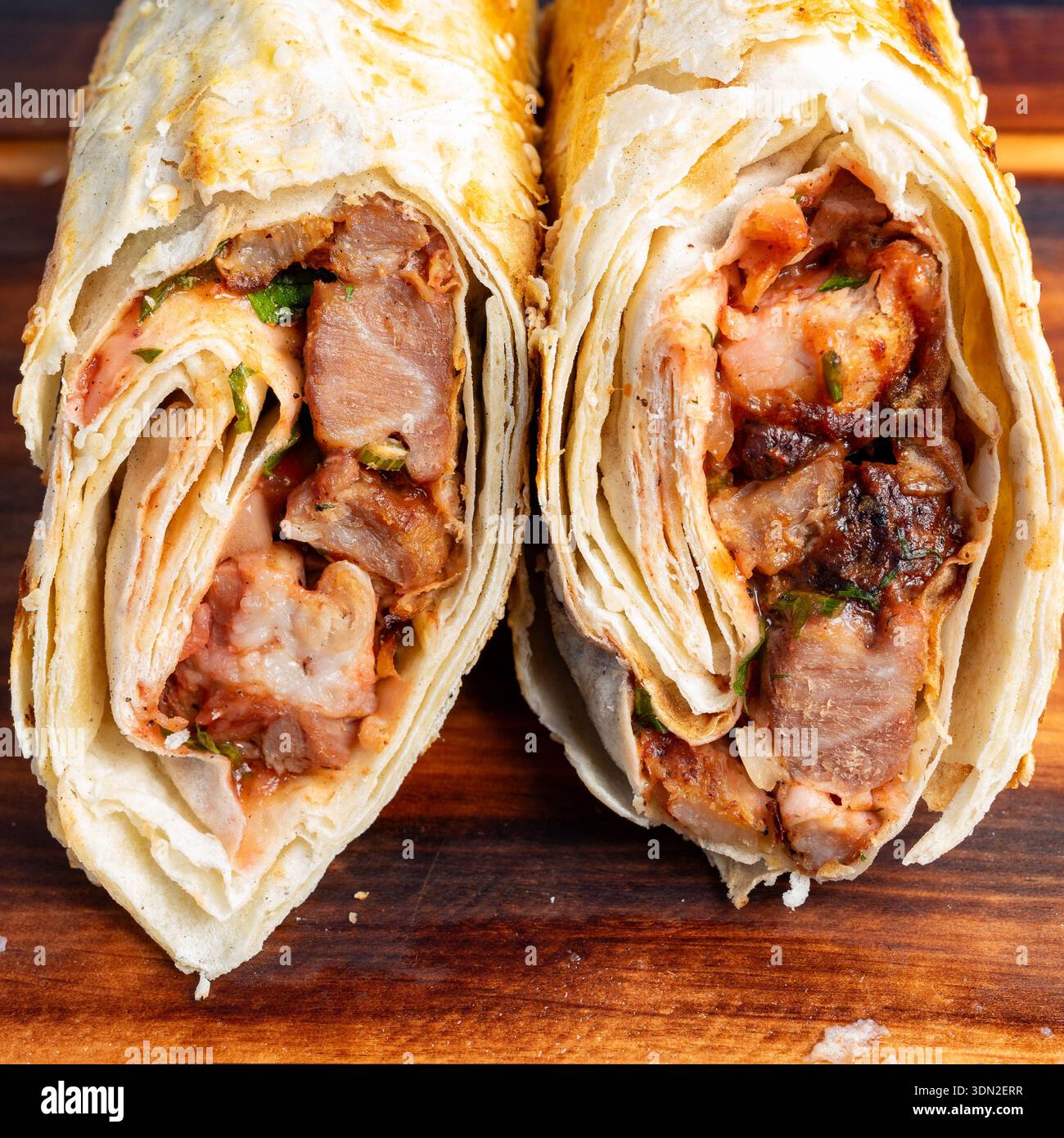 Vengono mostrati due involtini con strati di carne e verdure, preparati in uno stand di cibo di strada durante la serata. Foto Stock