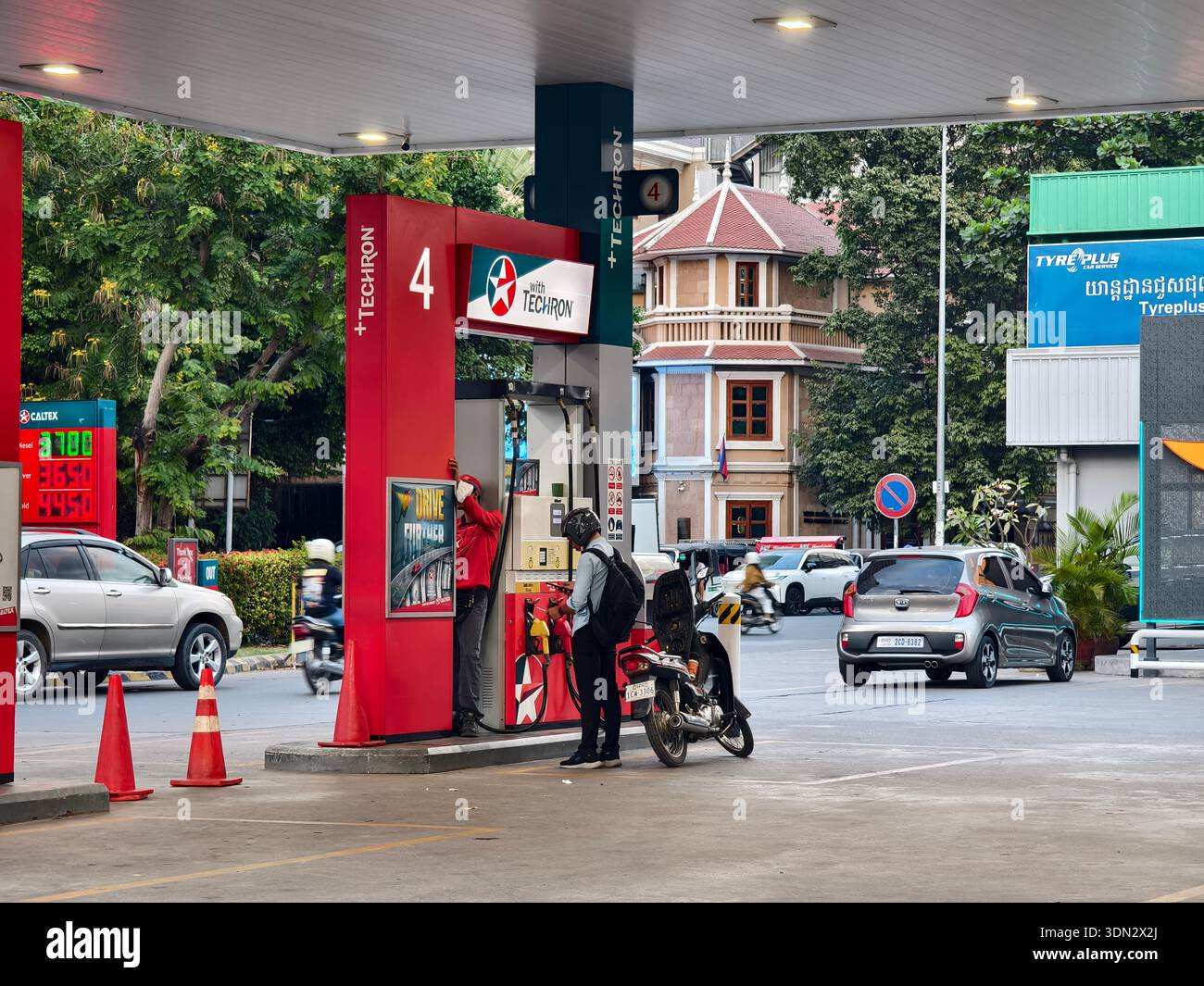Il lavoratore fa rifornimento di moto presso la stazione di servizio Caltex, marchio petrolifero della Chevron, utilizza la tecnologia di alimentazione "Techron". Phnom Penh, Cambogia Foto Stock