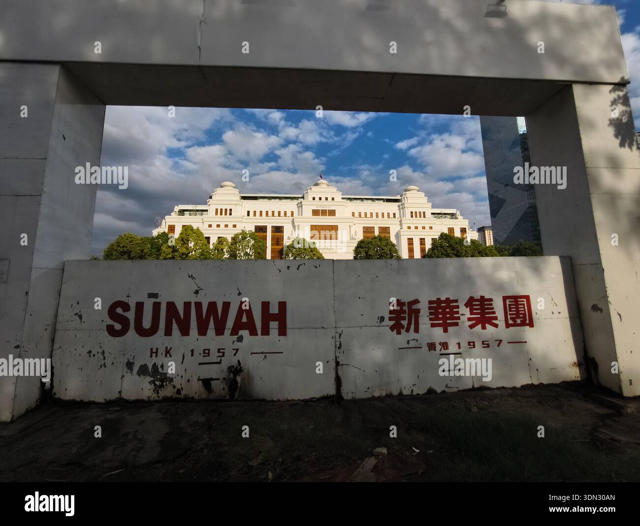 Edificio governativo parzialmente oscurato da barriere in cemento con il nome della società SUNWAH, Est 1957 a Hong Kong. Phnom Penh, Cambogia Foto Stock