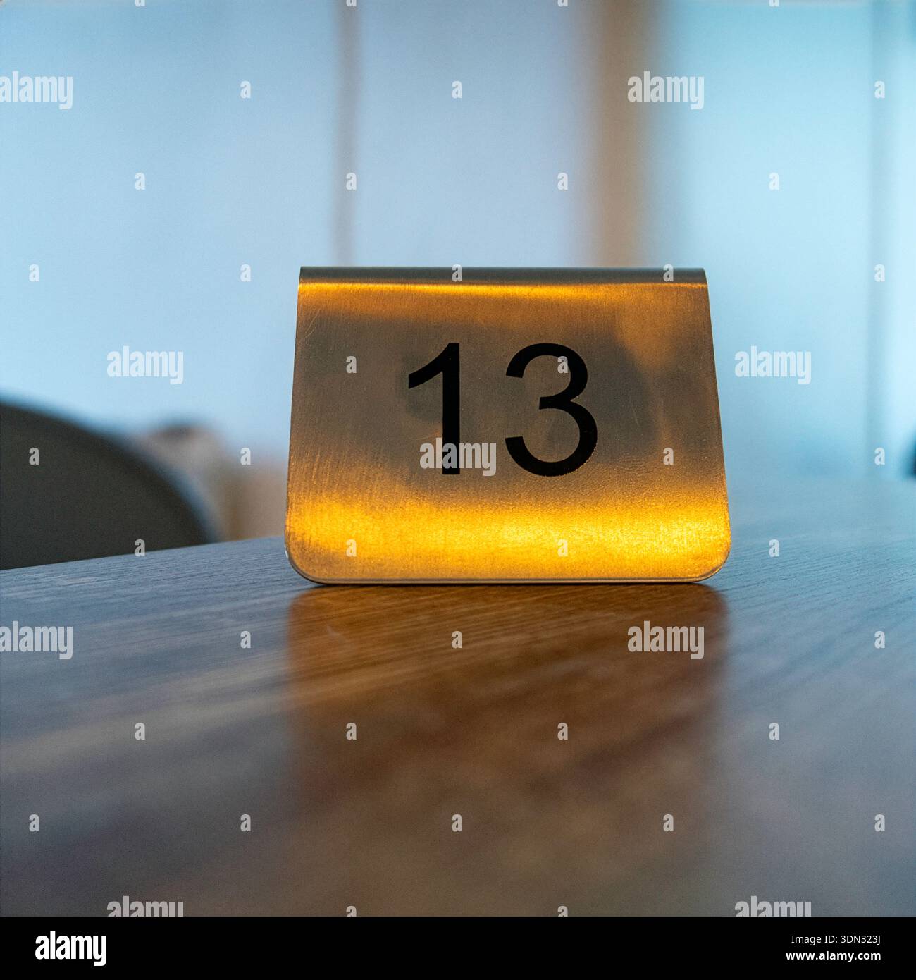 Un tavolo numero 13 e' illuminato da una luce calda, ideale per ristoranti, caffe', bar o ospitalita'. Foto Stock