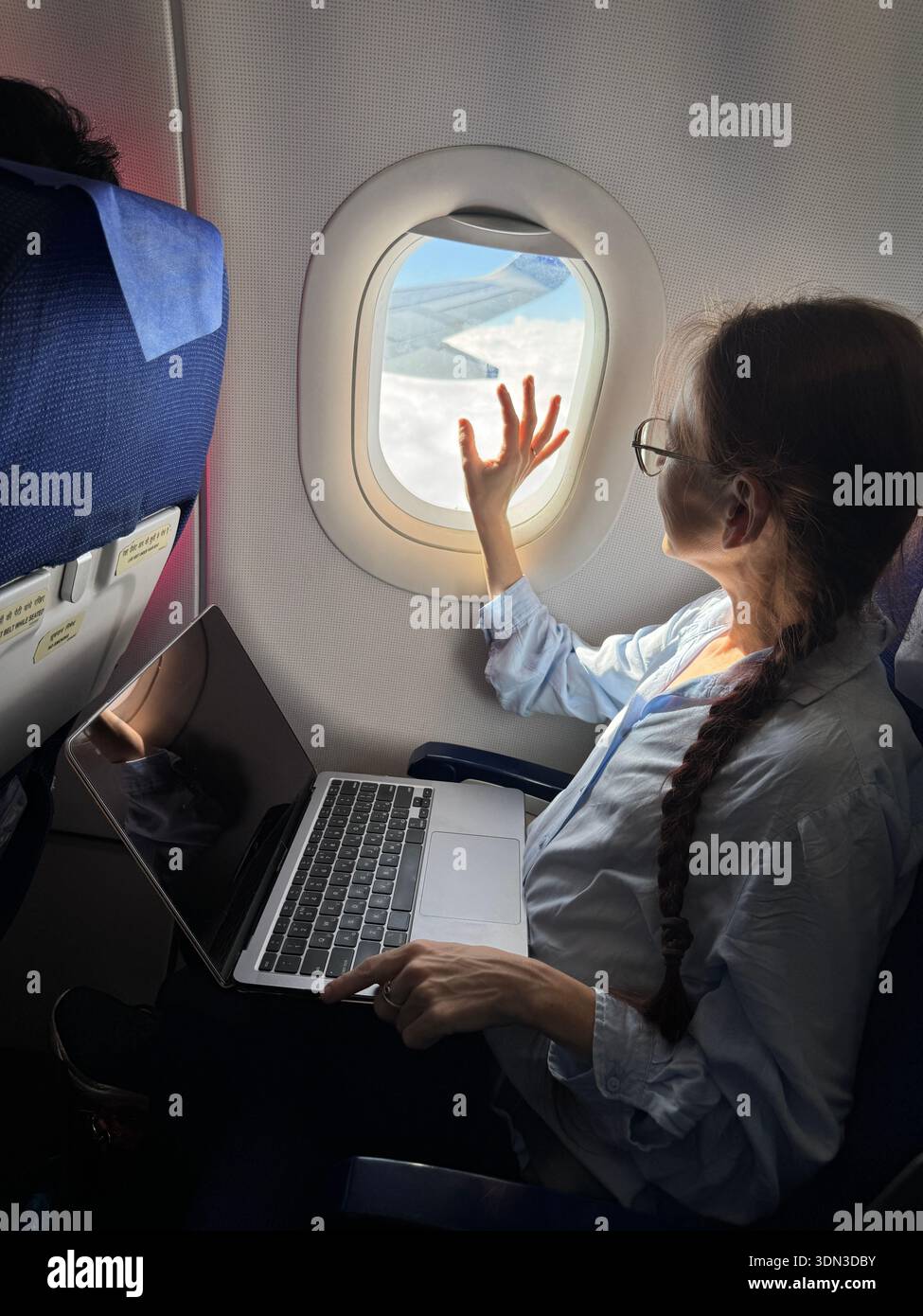 Atmosfera di viaggio tranquilla e di lusso con elegante passeggero al finestrino dell'aereo in una luce soffusa che cattura uno stile sobrio calma sicurezza e raffinatezza minimale Foto Stock