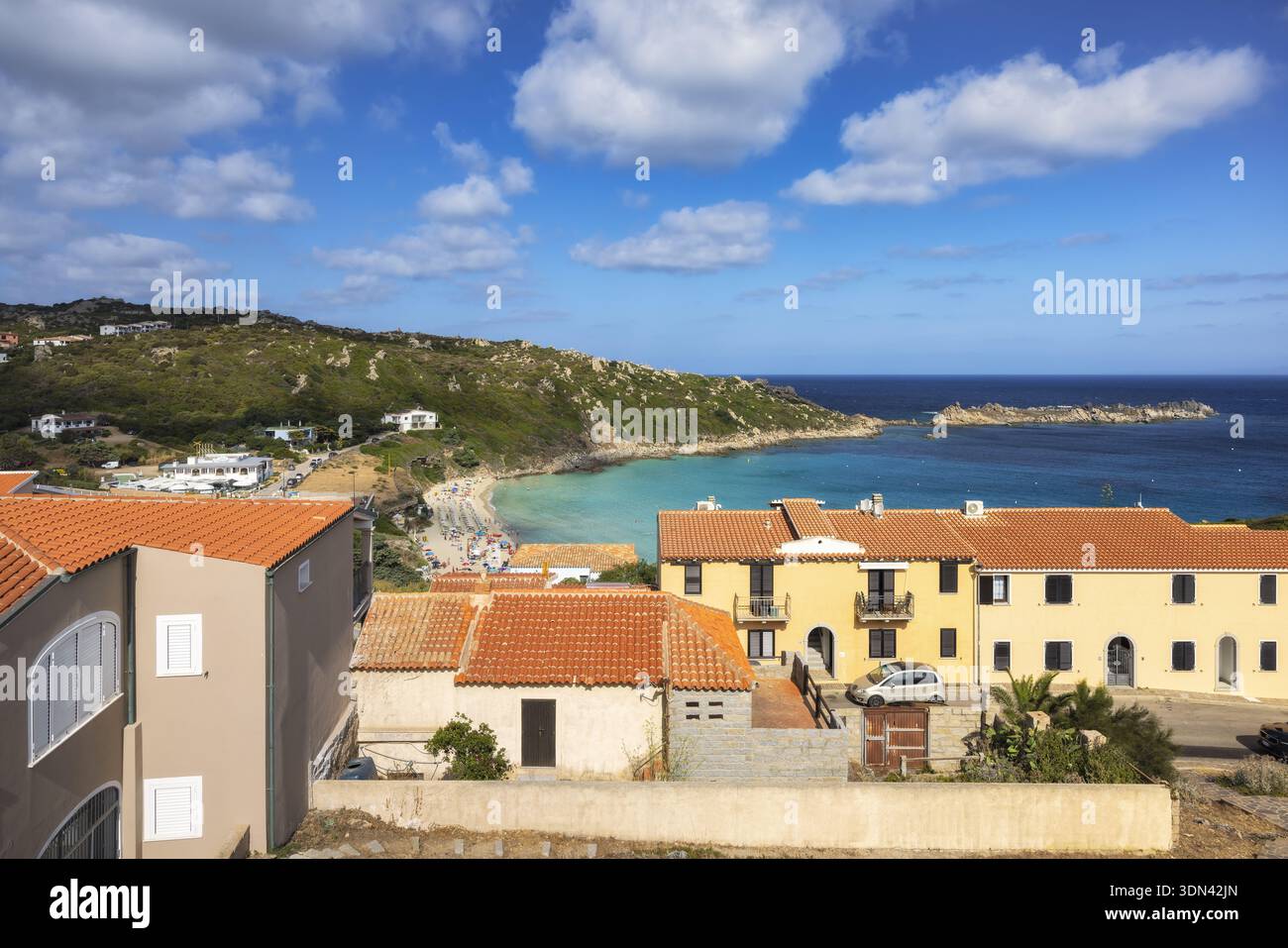 La vista dei tetti di terracotta e delle pareti beige incontra le acque turchesi sotto un cielo bruciato di nuvole, una vista costiera di serena bellezza, Santa Teresa Gallura Foto Stock