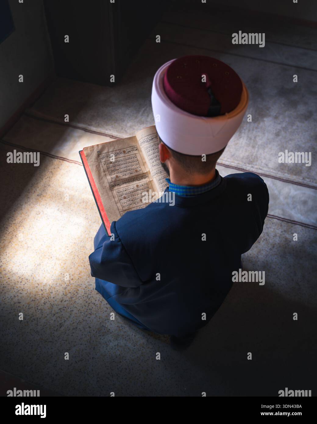 Travnik, Bosnia ed Erzegovina - 8 maggio 2025: Veduta di un uomo assorbito dalla lettura di un libro, luci e ombre danzanti nell'angolo della stanza. Foto Stock