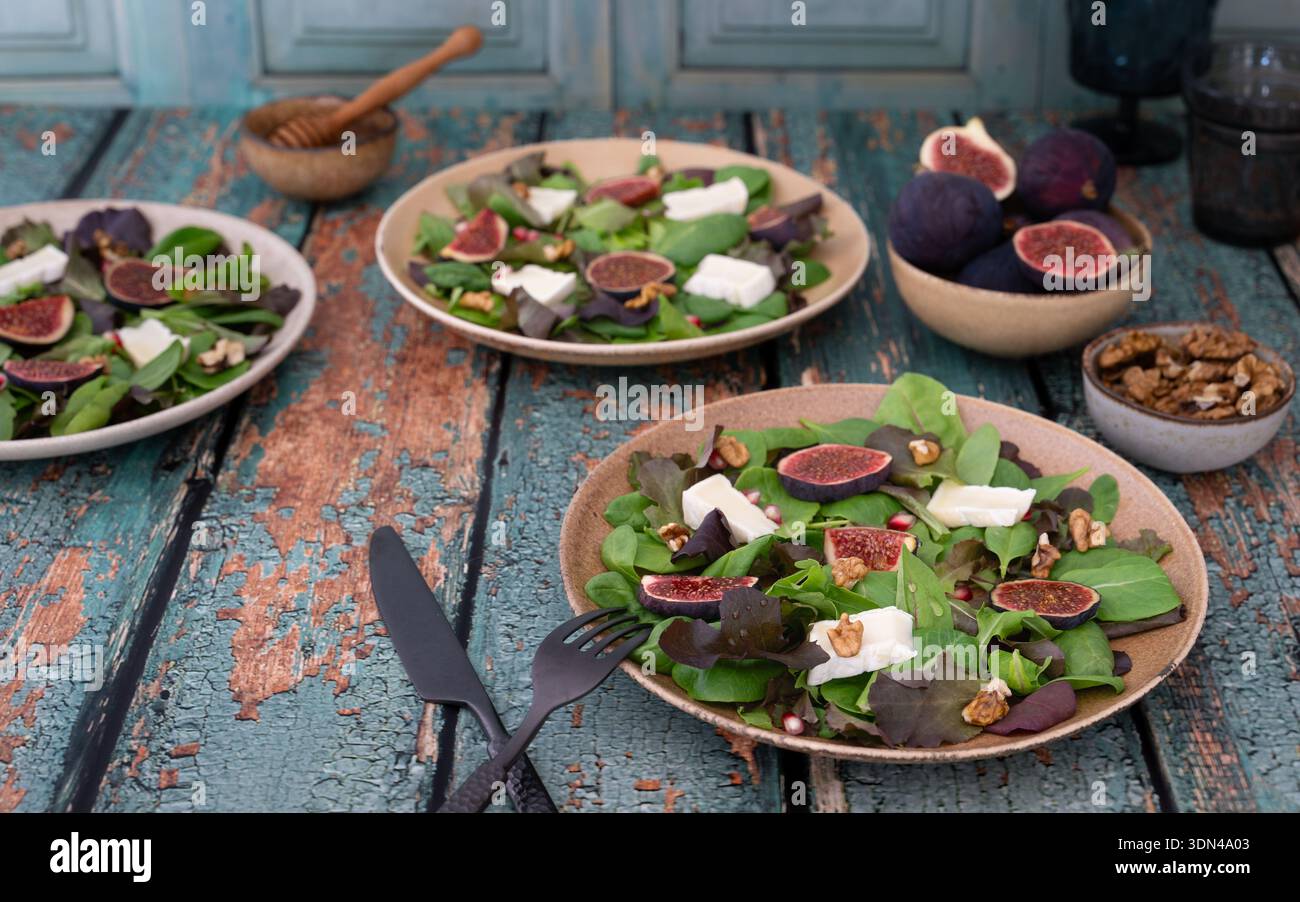Ampia scelta di insalate di spinaci e fichi disposte su un tavolo in legno blu Foto Stock