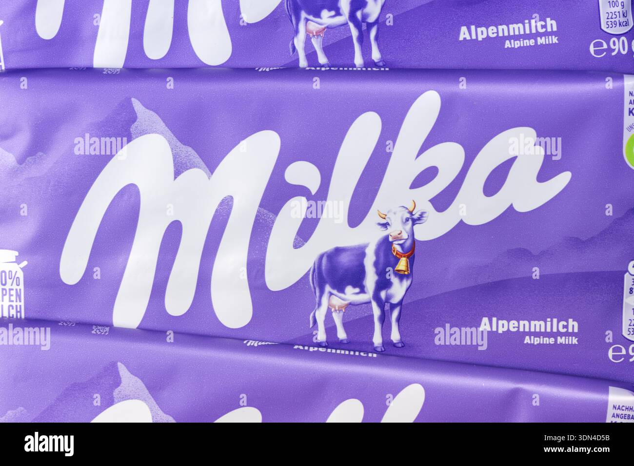 Stoccarda, Germania - 18 settembre 2025: Milka Chocolate 90g barretta Alpine Milk background close-up con logo aziendale a Stoccarda, Germania. Foto Stock