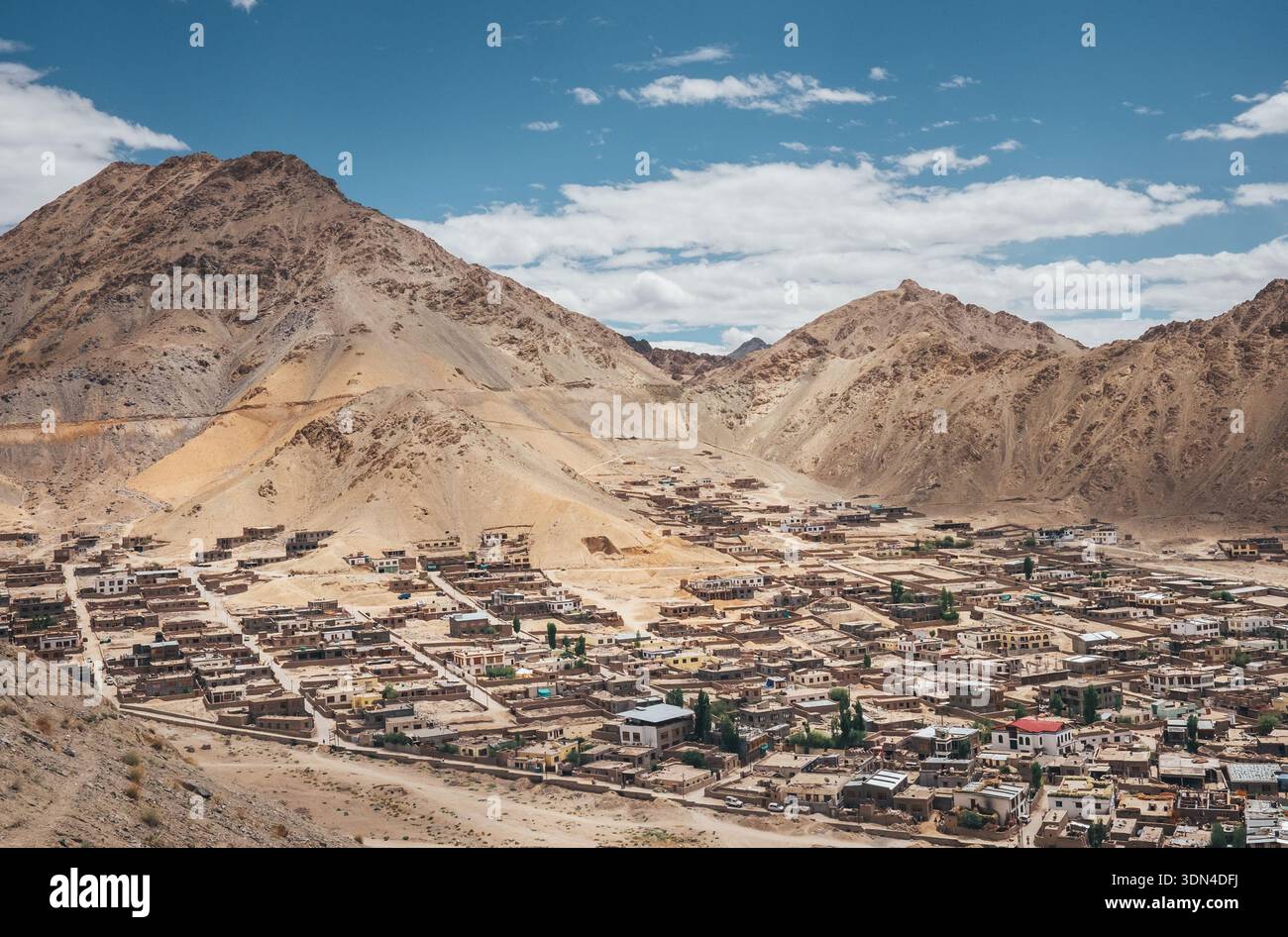 Vista panoramica dall'alto angolo della città di Leh, annidata nell'aspra valle montana dell'Himalaya sotto il cielo blu con nuvole bianche nella regione del Ladakh, nel nord dell'India Foto Stock