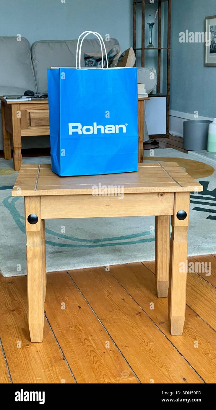 Borsa del rivenditore di abbigliamento Rohan con nuovo acquisto di abbigliamento sportivo su un piccolo tavolo di legno nel soggiorno, Regno Unito Foto Stock