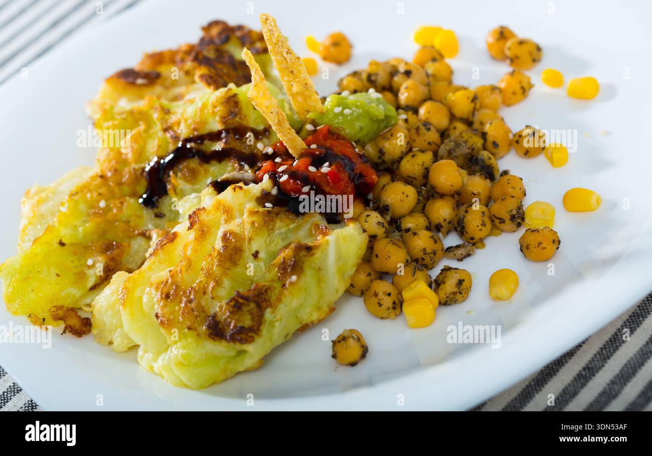 Fotografia di piatto con foglie di cavolo in pastella con garbanzos e salsa Foto Stock