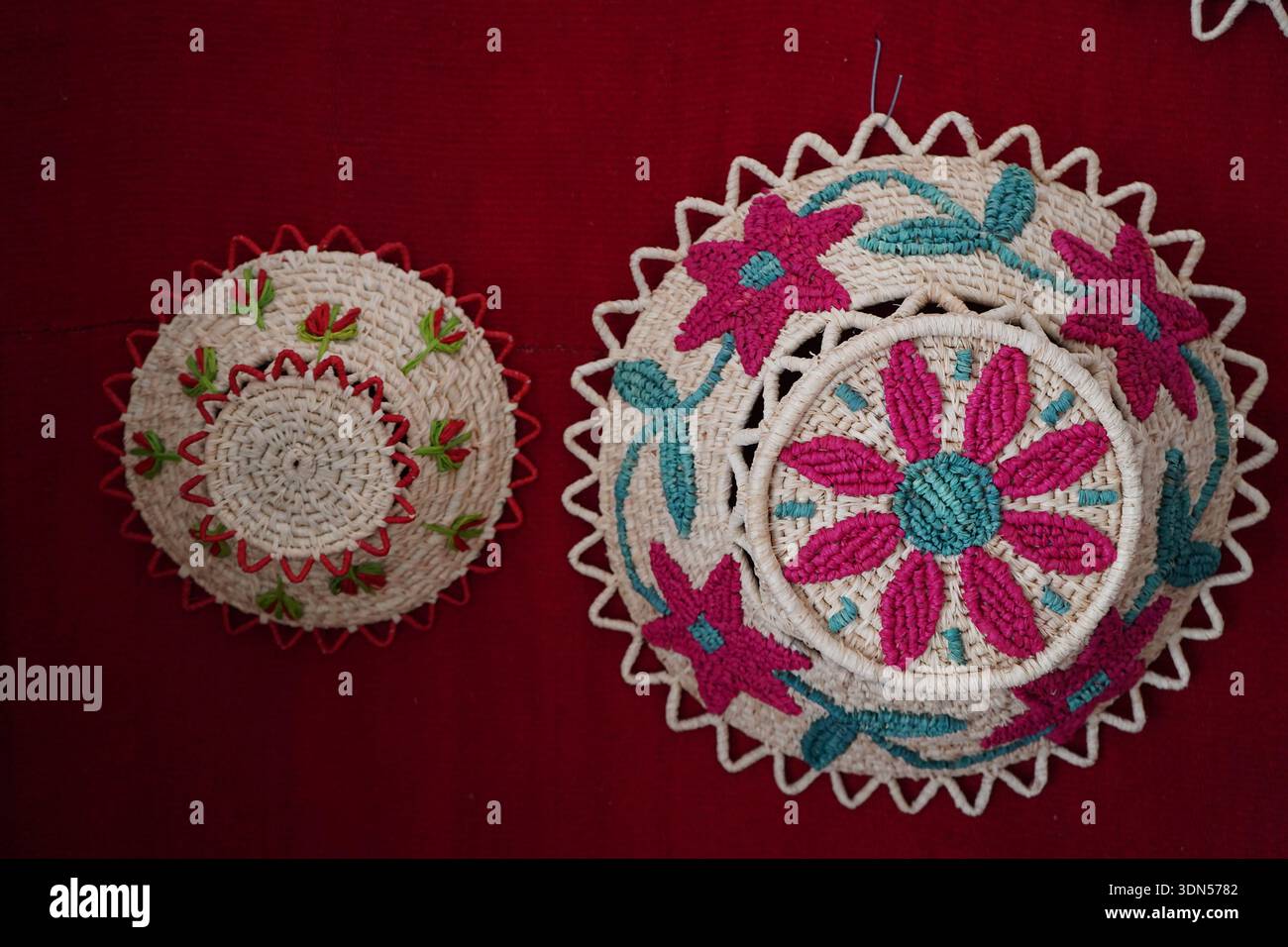 Cestini lavorati a mano con vivaci ricami floreali in rosa e tè. Mostra artistica di cestini greci tradizionali e folklore mediterraneo Foto Stock
