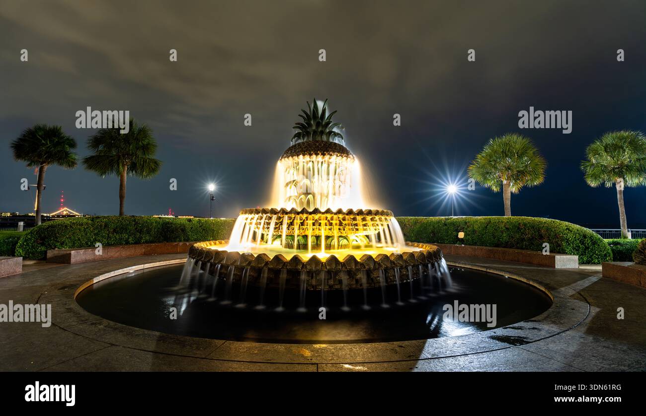 L'iconica fontana degli ananas di Charleston, South Carolina, presenta un'architettura in pietra a gradoni illuminata e palme nel Waterfront Park di notte Foto Stock