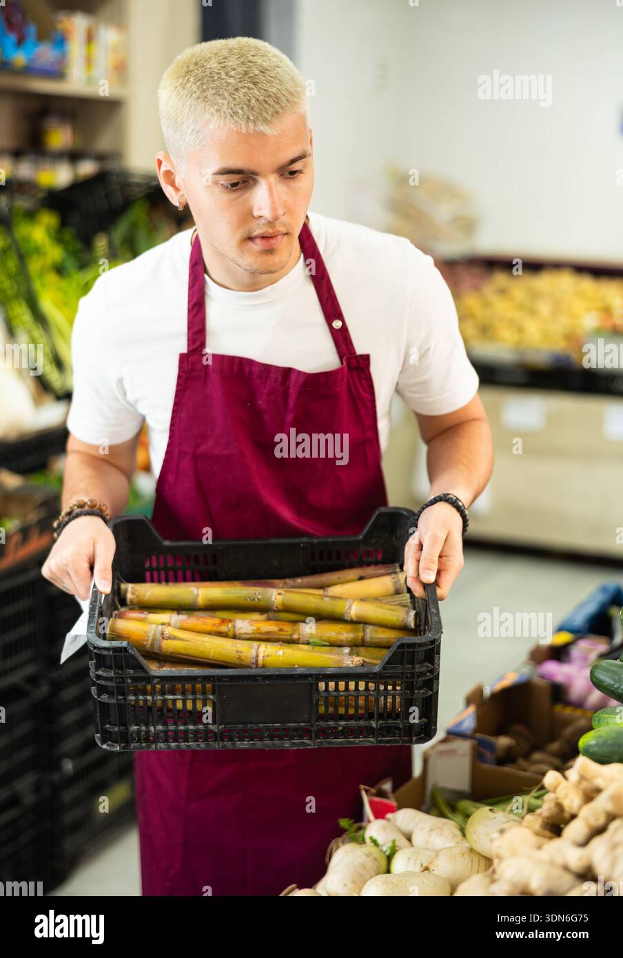 Il dipendente del supermercato porta una scatola di asparagi Foto Stock