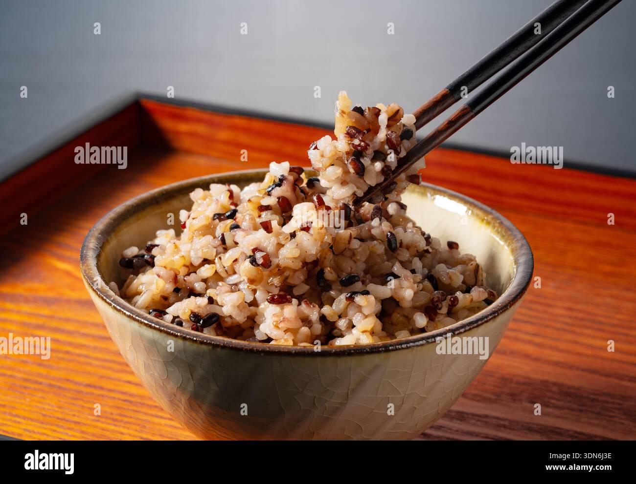 Ciotola di riso multigrano giapponese con bastoncini su un vassoio di legno, mangiare sano Foto Stock