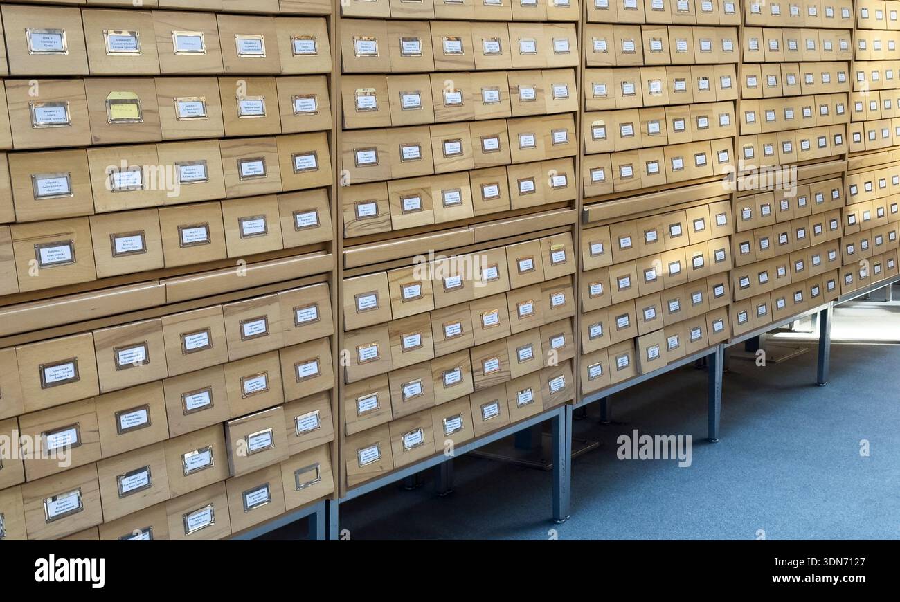 grande sistema di cataloghi di carte in legno con centinaia di cassetti etichettati utilizzati per la conservazione di documenti di archivio. La struttura ripetitiva enfatizza l'ordine, classifica Foto Stock