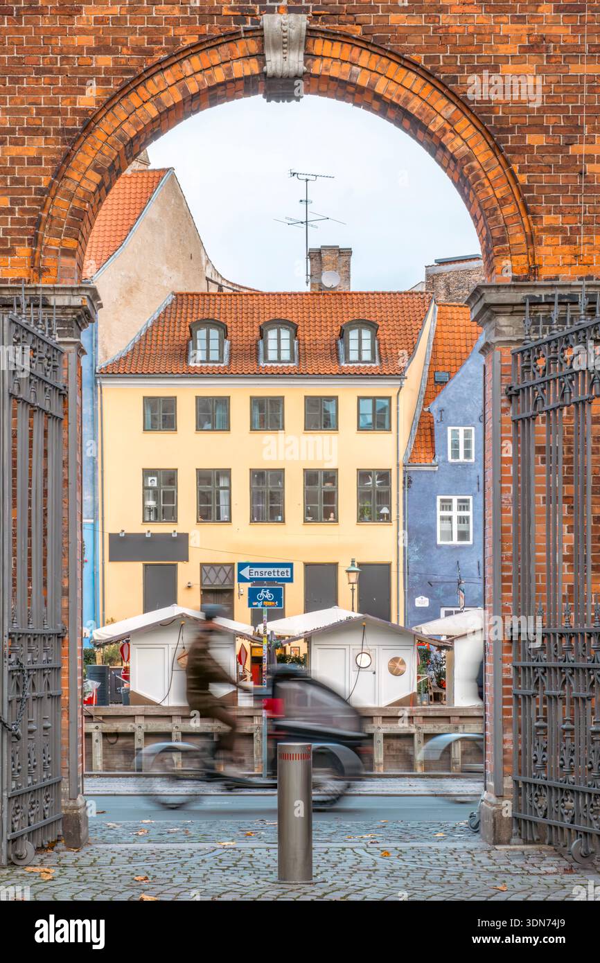 Ciclista che passa attraverso Brick Archway nell'area del canale Nyhavn di Copenaghen, Danimarca Foto Stock