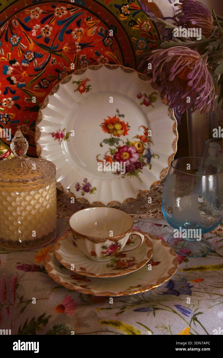 Una tazza di tè o caffè con motivo floreale e altri oggetti in vetro e cristallo per l'uso quotidiano in casa. Foto Stock