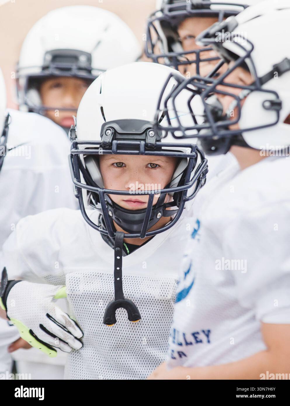 Ragazzo che guarda la macchina fotografica con un casco da calcio Foto Stock