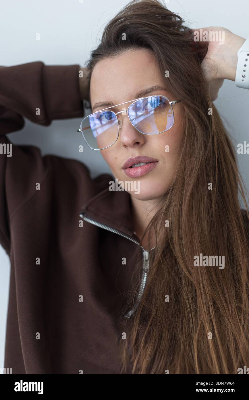 Giovane donna che indossa occhiali protettivi blu che bloccano la luce per ridurre l'affaticamento degli occhi digitali. Telai in metallo argento con rivestimento antiriflesso. Concetto di Foto Stock