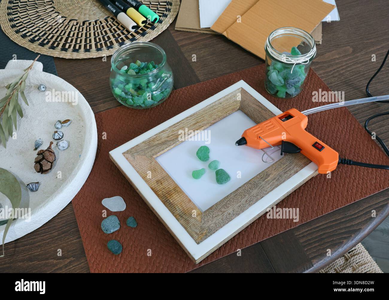 Vetro marino nel telaio. Fare arte con materiali naturali. Incollare la pistola e il punzone per l'immagine. Hobby e creatività. Riutilizzo e natura, ecologia. Foto Stock