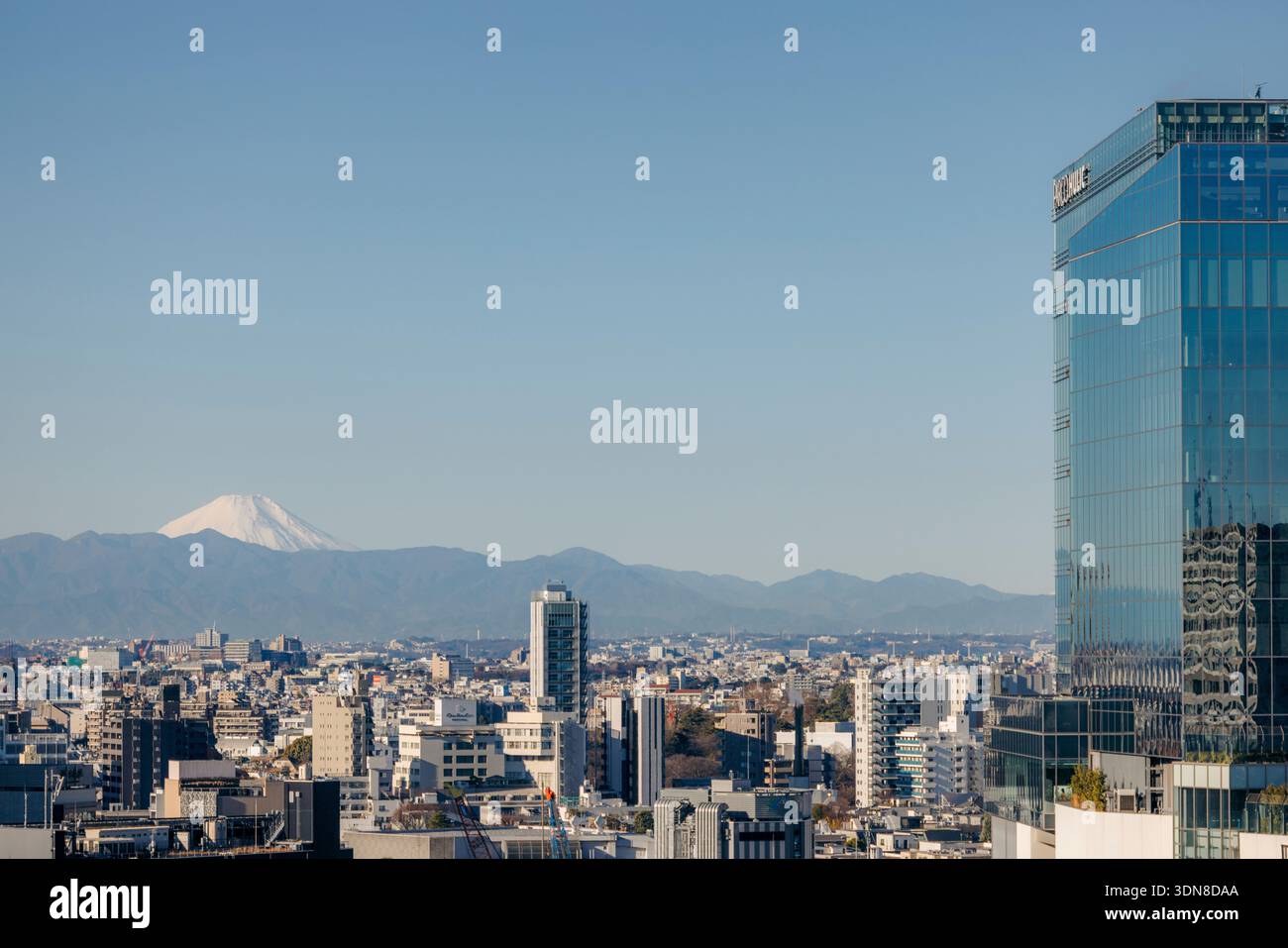 Skyline urbano con un grattacielo di vetro e il Monte Fuji sullo sfondo in una giornata limpida. Tokyo, Giappone Foto Stock
