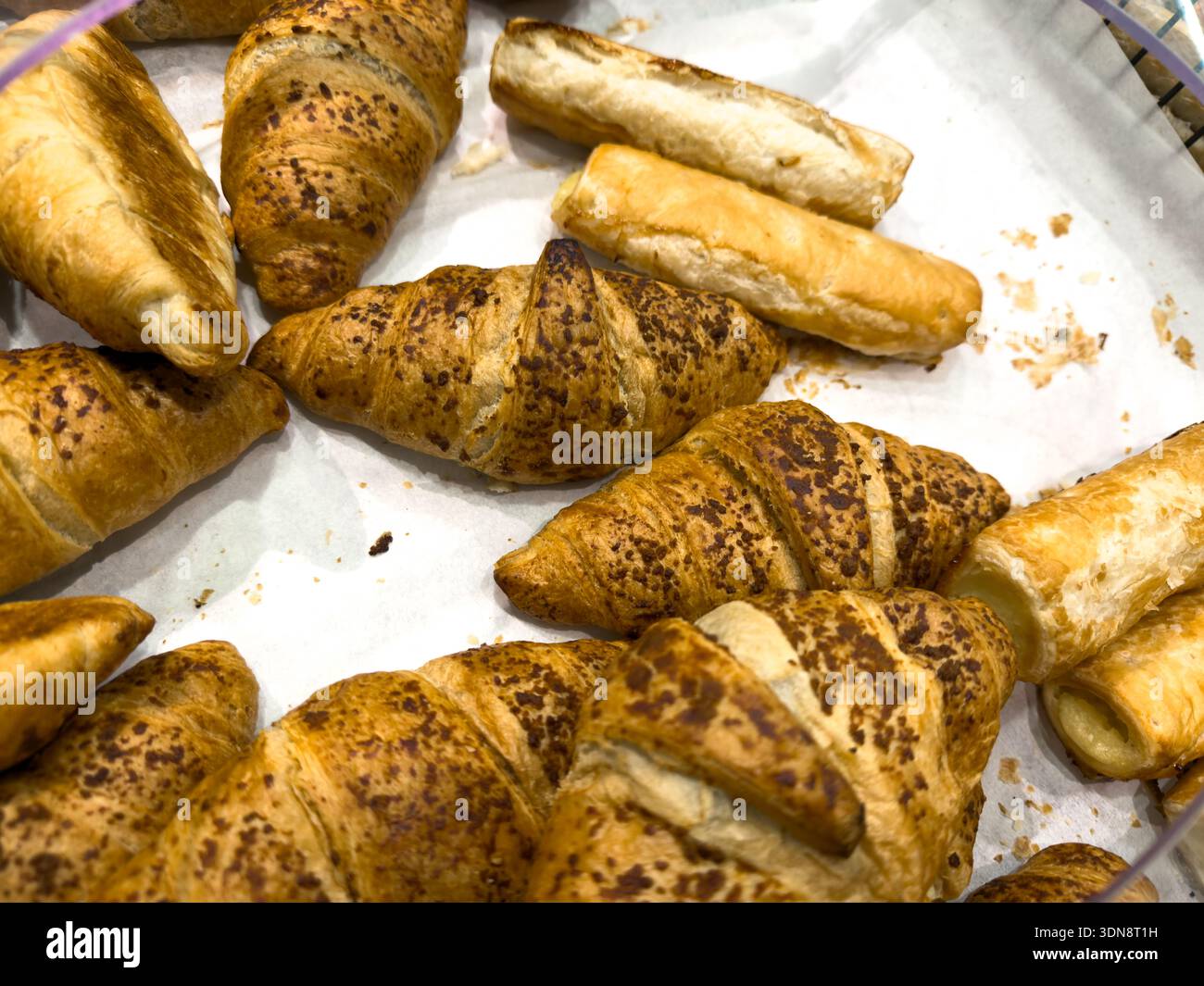 Primo piano di croissant dorati con cime macchiate e dolci croccanti e salati, perfetti per un'allettante esposizione di prodotti da forno o una deliziosa colazione Foto Stock