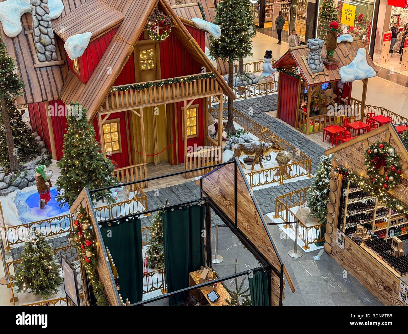 Vista sopraelevata di un festoso mercatino di Natale al coperto, con incantevoli bancarelle in legno, alberi lucenti e neve, che creano un'atmosfera deliziosa per lo shopping natalizio Foto Stock