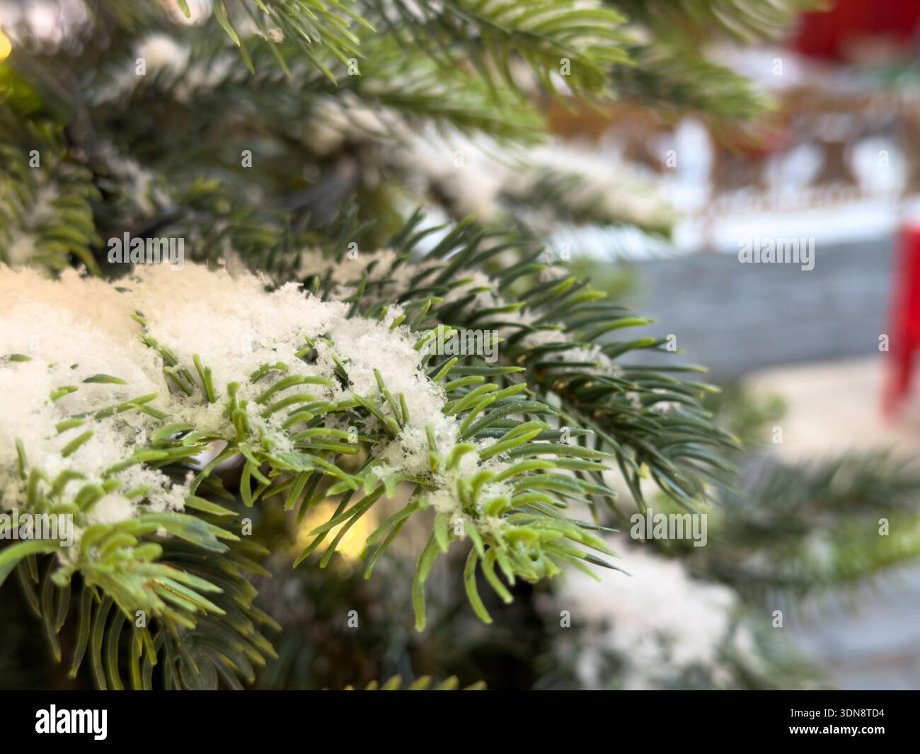 Vista ravvicinata di un lussureggiante ramo di pino artificiale ricoperto di neve bianca scintillante, che cattura perfettamente l'essenza del Natale, festivo e stagionale Foto Stock