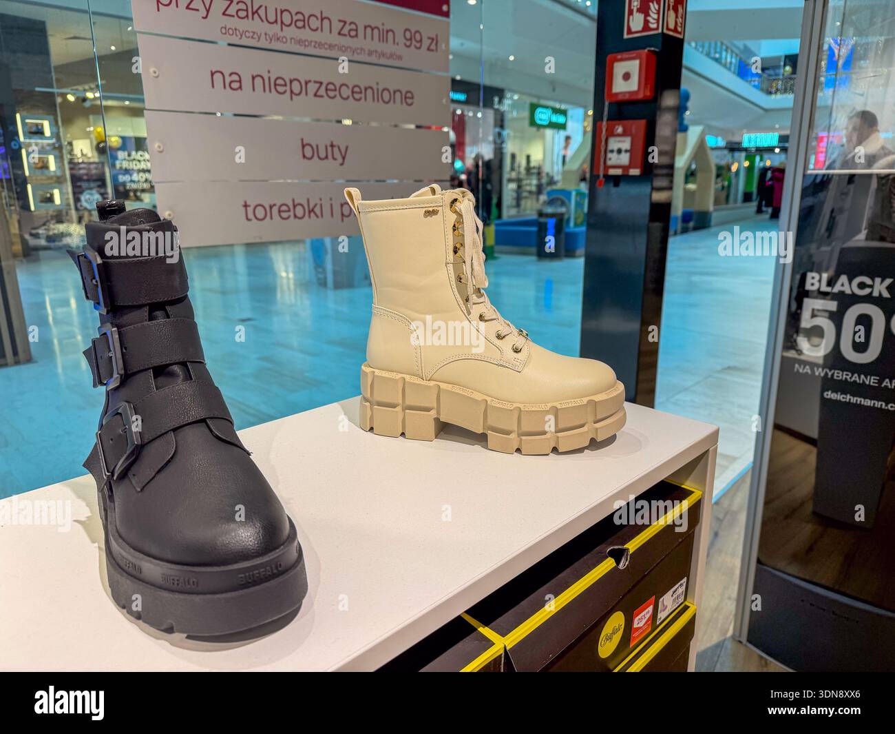 Poznan, Polonia - 28 novembre 2025: Stivali da combattimento a piattaforma nera e cremosa di BUFFALO esposti su uno stand bianco, attirando gli acquirenti in un ambiente contemporaneo Foto Stock