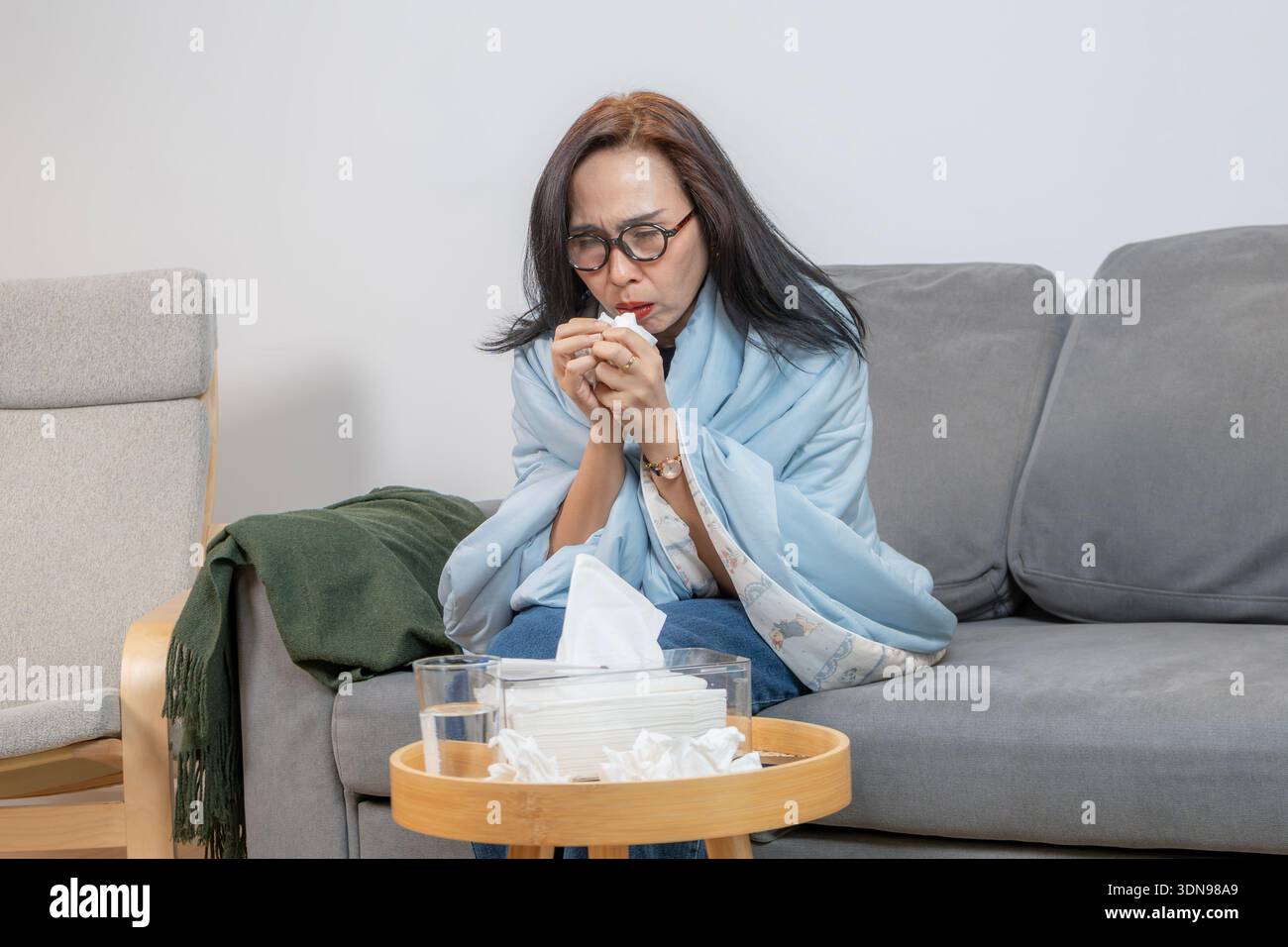 Una giovane donna malata prende la medicina e si riposa a casa, concentrandosi sull'autoassistenza, il recupero, la consapevolezza della salute e il trattamento domiciliare. Foto Stock