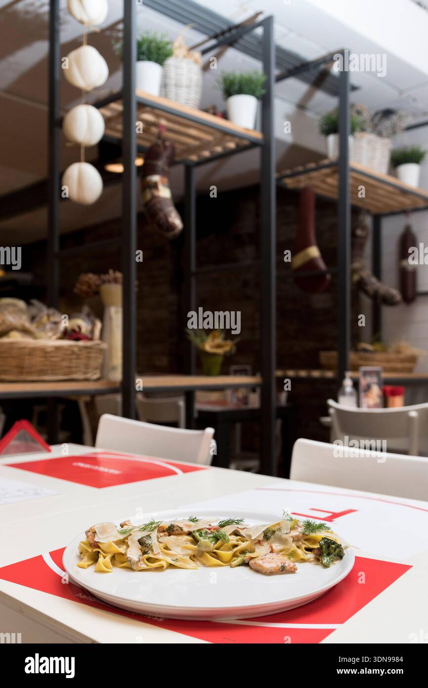 tagliatelle cremose condite con teneri pezzi di pollo alla griglia e guarnite con erbe fresche, perfettamente abbinate a un fresco bicchiere di bianco vincente Foto Stock