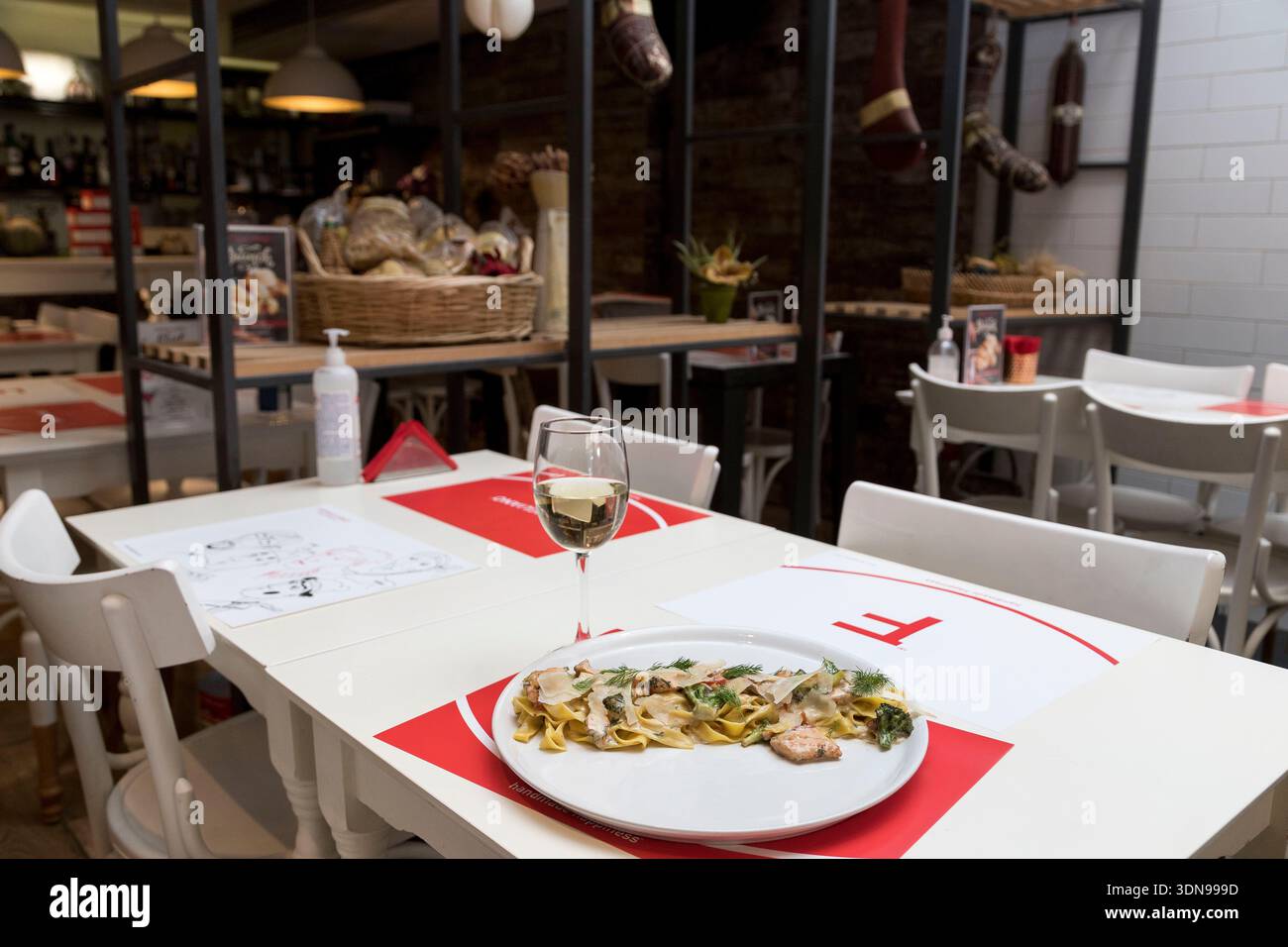 tagliatelle cremose condite con teneri pezzi di pollo alla griglia e guarnite con erbe fresche, perfettamente abbinate a un fresco bicchiere di bianco vincente Foto Stock