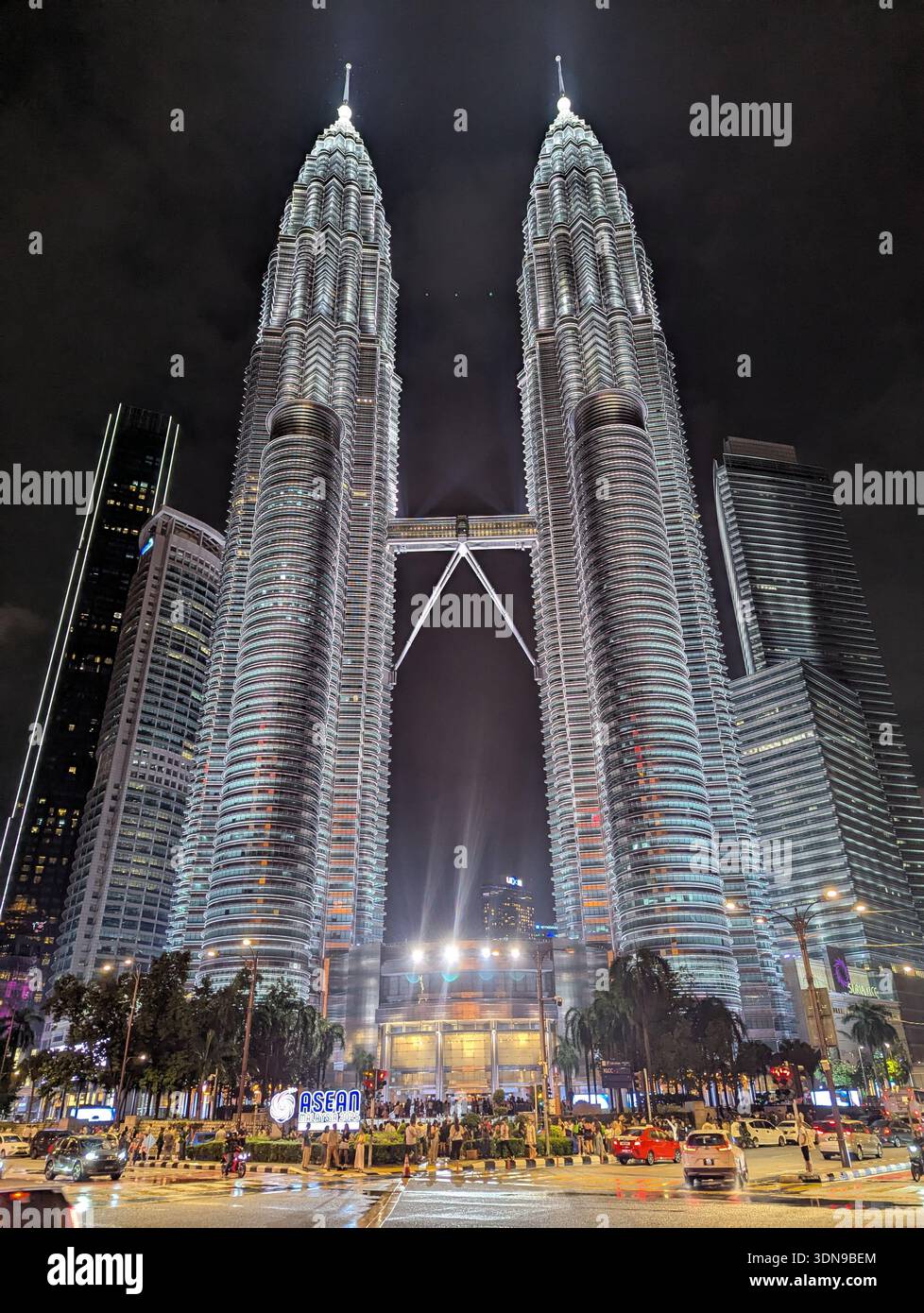 Le Petronas Twin Towers illuminate di notte, un famoso monumento e simbolo di Kuala Lumpur, Malesia, con il ponte sospeso e la città circostante - Immagine stock catturata con smartphone