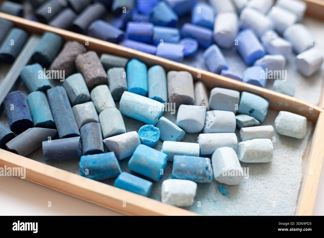 Set di pastelli pastello morbidi in blu, verde acqua in una scatola di legno per artisti. Pastelli rotti, vista dall'alto. Forniture d'arte. Foto Stock