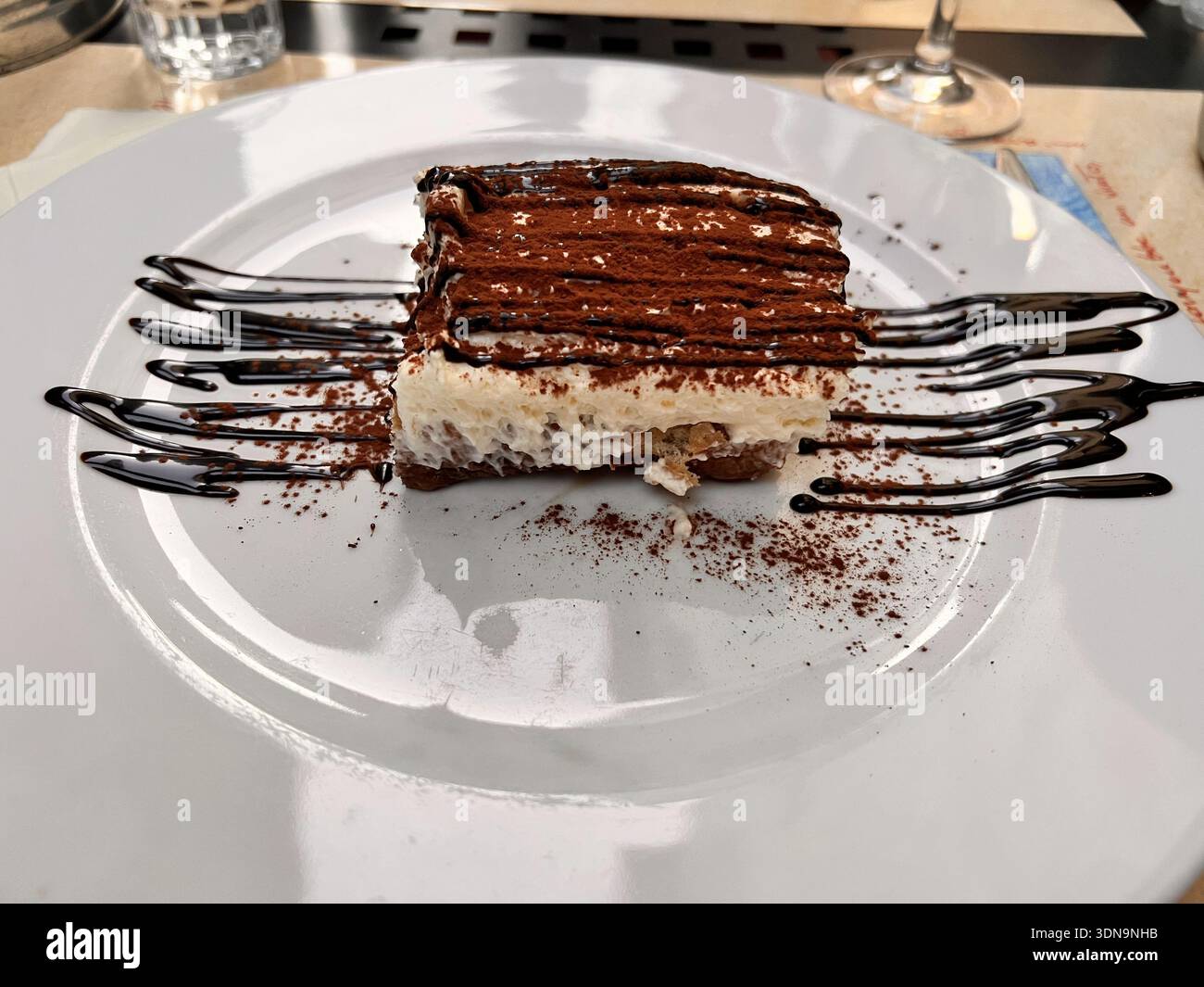 Tiramisù classico con cacao e gocciolatoio di cioccolato su un elegante piatto di dessert - Immagine stock catturata con smartphone