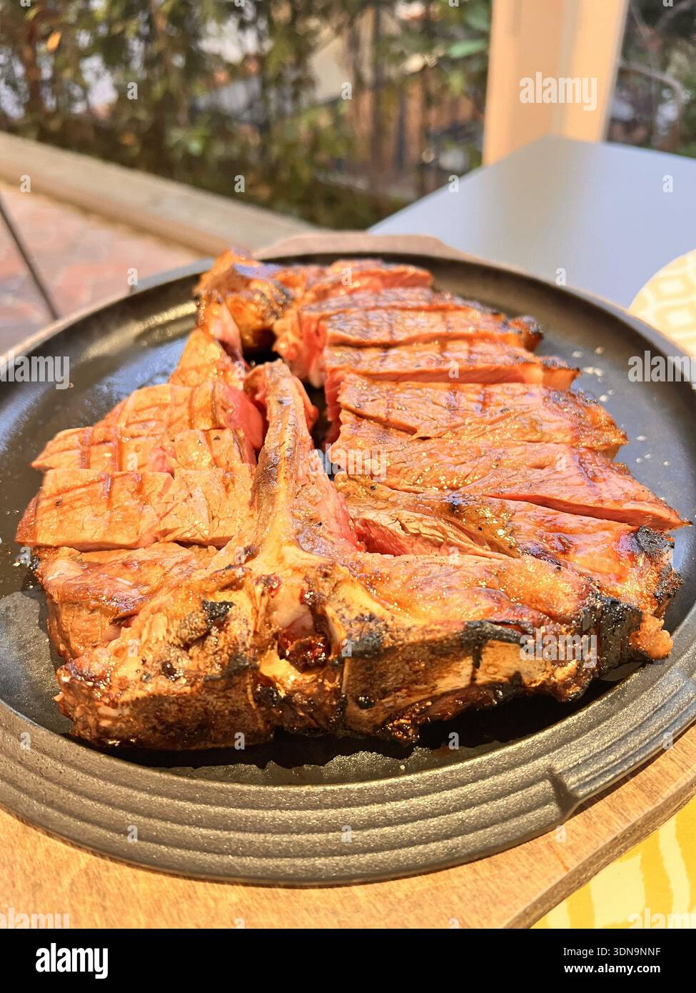 Bistecca grigliata a fette su piatto nero rustico - Immagine stock catturata con smartphone