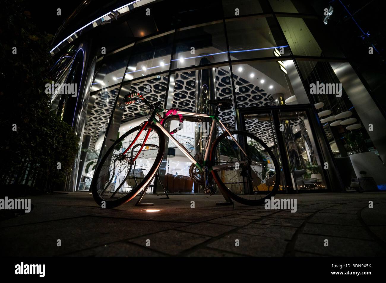 Scena notturna di strada a Varsavia, in Polonia, con una bicicletta parcheggiata sotto le calde luci della città. Atmosfera urbana con toni moody e architettura europea nel Foto Stock