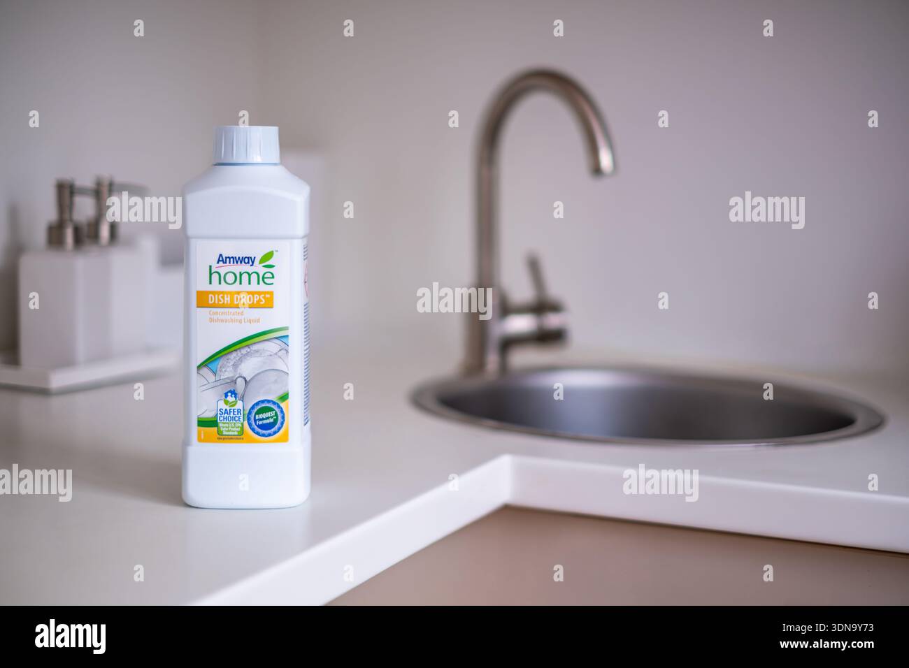 Riga, Lettonia - 8 febbraio 2026: Amway Dish Drops detersivo esposto su un bancone bianco della cucina accanto a un acciaio inossidabile Foto Stock