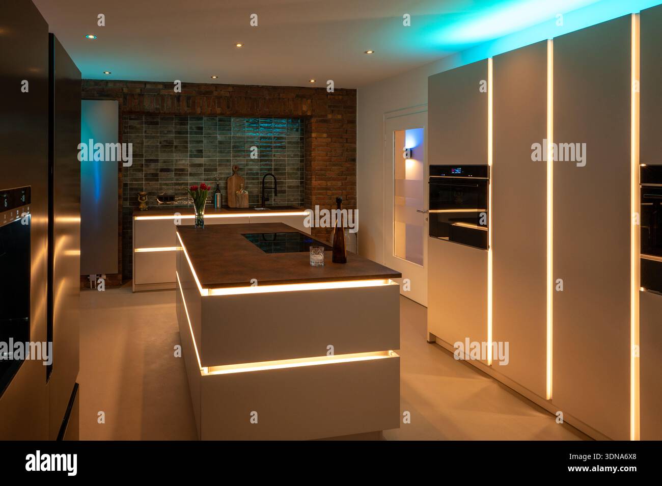 Design degli interni di lusso della cucina: Frigorifero affiancato e pavimento senza cuciture con moderna illuminazione ambiente a LED e controsoffitto in acciaio Corten Foto Stock