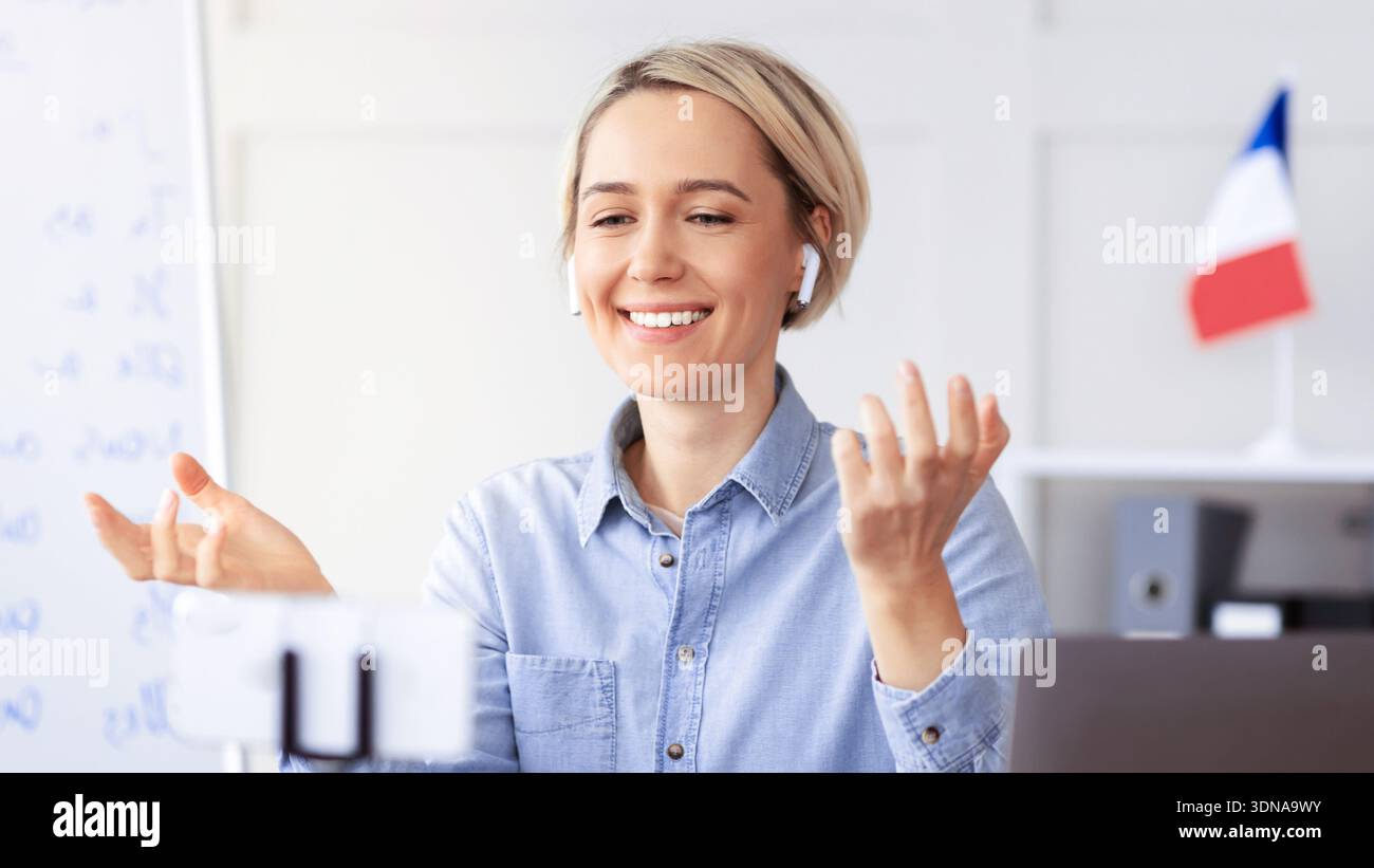 Una donna si impegna a conversare online mentre utilizza gli auricolari in ufficio nel pomeriggio Foto Stock