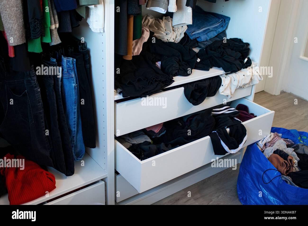 Armadio con armadio disordinato, completo di panni da donna aperti e appesi Foto Stock