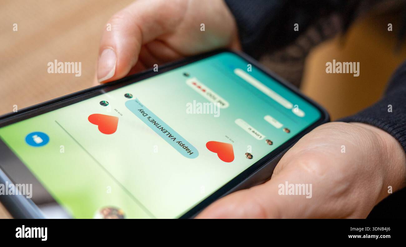 Primo piano dei messaggi di San Valentino sullo smartphone in mano. Foto Stock