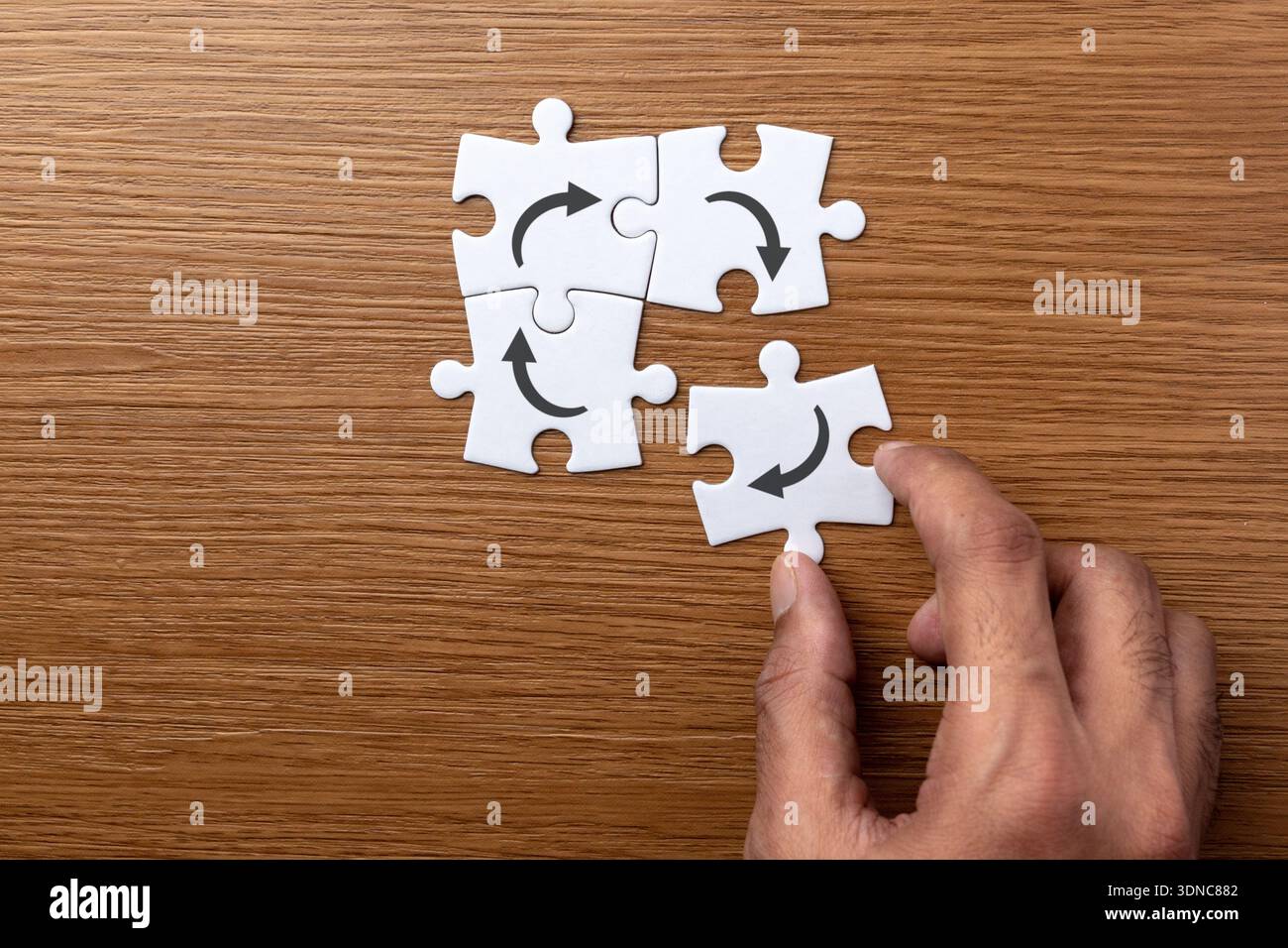 Una mano che posiziona un puzzle bianco con un'icona a forma di freccia circolare. Processo, flusso di lavoro, riciclaggio, concetto di iterazione. Foto Stock